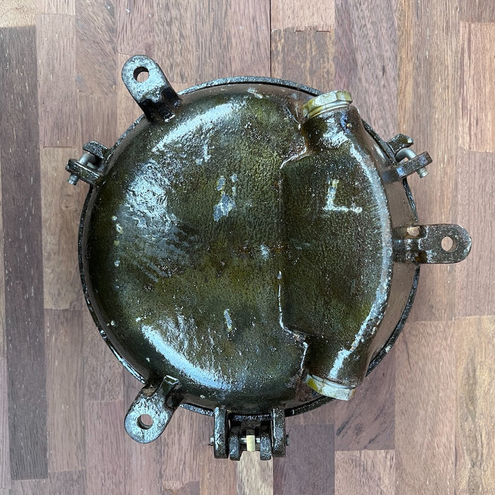 Iron round bulkhead light showing weathered patina and iron construction