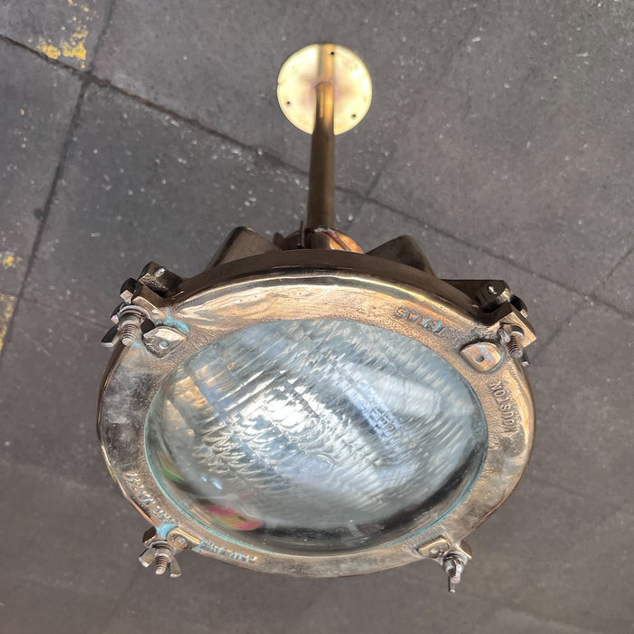 Underside view of polished Pauluhn brass ship spotlight ceiling light with wing-nut lens clamps