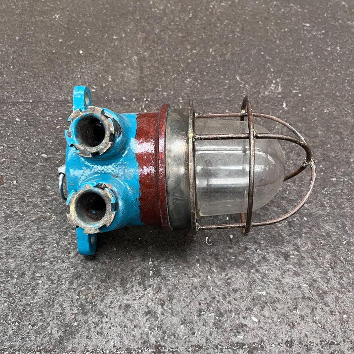 Salvaged blue and red iron marine security light with glass dome and steel cage, front view