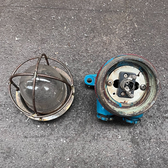 Repainted blue and red cast iron ship light with caged glass dome, viewed from above