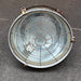Front view of vintage VEB cargo ceiling light with circular wire guard, glass cover and brass toggle clamps