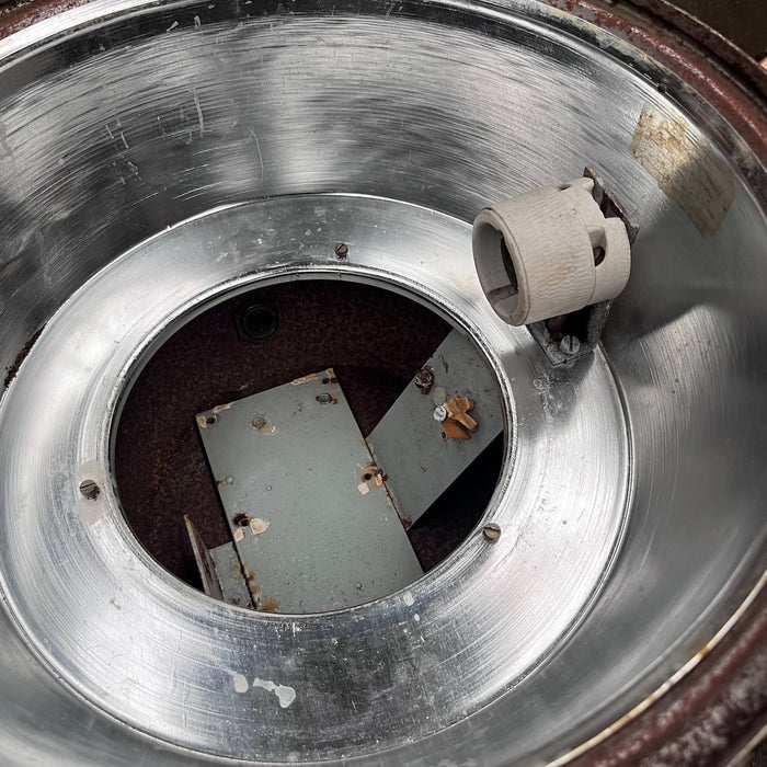 Inside of VEB industrial ceiling light showing polished reflector, ceramic lamp holder and internal mounting plates