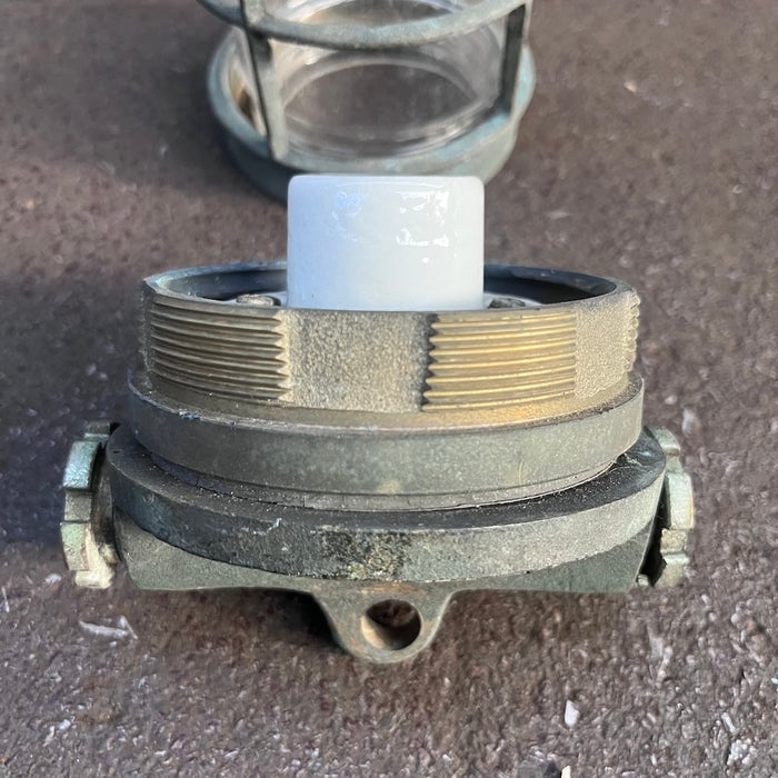 Threaded brass base and ceramic lampholder of a salvaged marine cage light with hanging eye