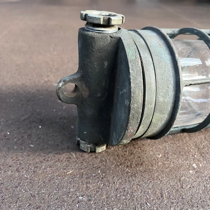 Side view of a salvaged brass marine cage light showing the hanging eye and gland nuts