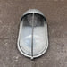 Side view of oval bulkhead light showing half-hood shield and guard bar