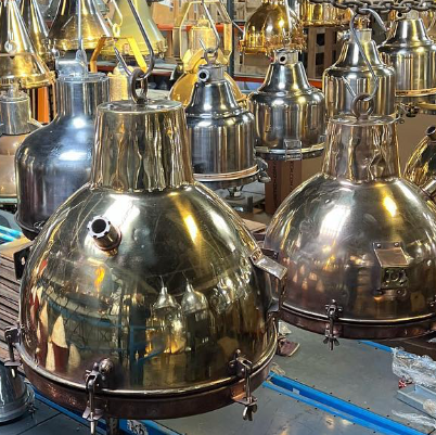 Collection of brass and metal pendant lights on a workshop floor.